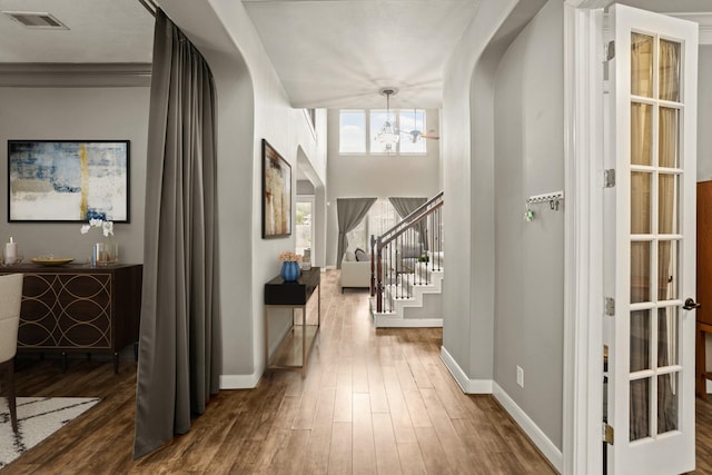 corridor featuring hardwood / wood-style flooring, crown molding, and an inviting chandelier