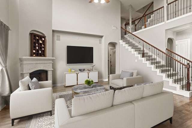 living room with ceiling fan, hardwood / wood-style floors, and a high ceiling