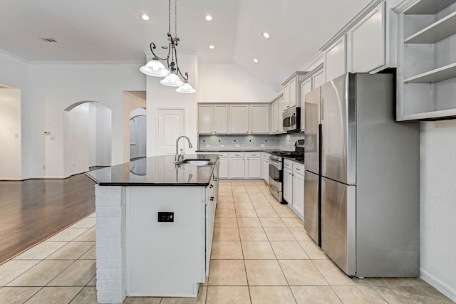 kitchen with light tile patterned floors, crown molding, appliances with stainless steel finishes, and a kitchen island with sink