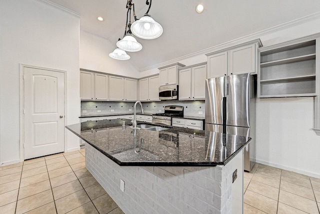 kitchen featuring sink, light tile patterned flooring, dark stone countertops, a center island with sink, and stainless steel appliances