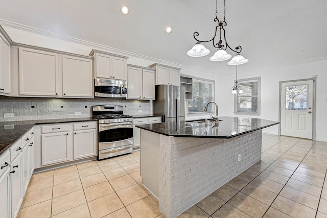 kitchen featuring pendant lighting, appliances with stainless steel finishes, sink, light tile patterned floors, and a center island with sink