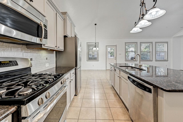 kitchen with appliances with stainless steel finishes, sink, decorative light fixtures, a center island with sink, and light tile patterned flooring