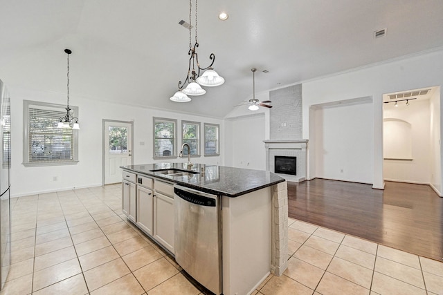 kitchen with dishwasher, ceiling fan, sink, light tile patterned flooring, and a center island with sink