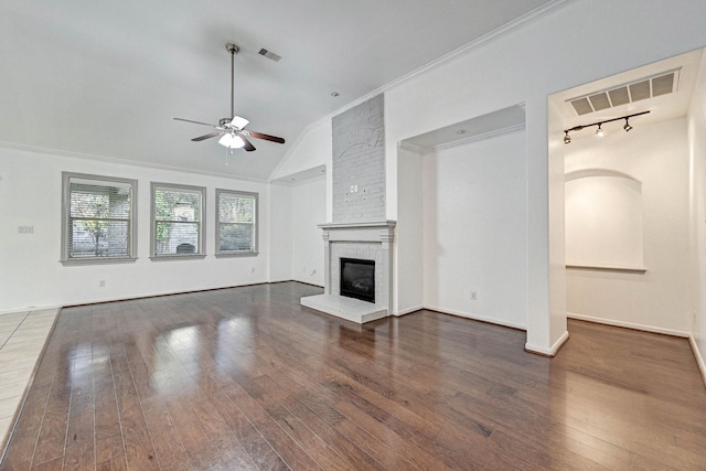 unfurnished living room featuring vaulted ceiling, a fireplace, ornamental molding, dark wood-type flooring, and ceiling fan