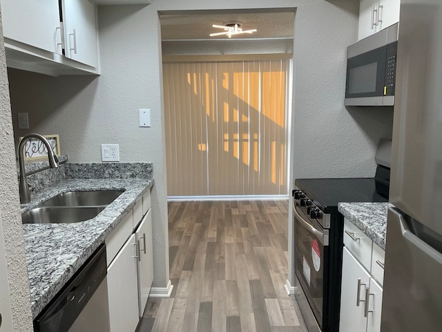 kitchen with sink, white cabinetry, light stone countertops, and appliances with stainless steel finishes