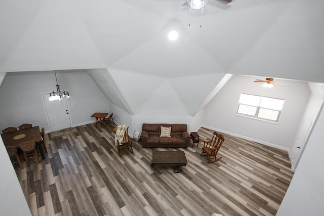 living area featuring hardwood / wood-style flooring, ceiling fan with notable chandelier, and vaulted ceiling