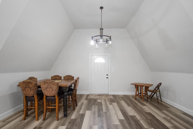 dining space with vaulted ceiling, an inviting chandelier, and wood-type flooring