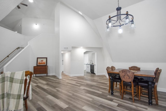 dining room with hardwood / wood-style floors, high vaulted ceiling, and a notable chandelier