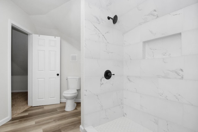 bathroom featuring hardwood / wood-style flooring, toilet, and a tile shower