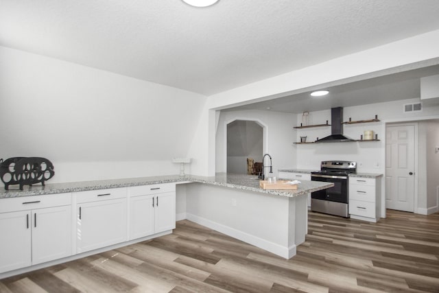 kitchen featuring stainless steel electric range, white cabinets, sink, kitchen peninsula, and wall chimney exhaust hood