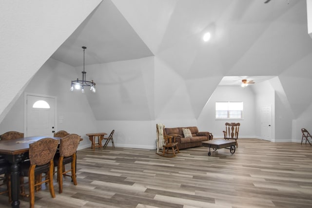 dining area with vaulted ceiling, ceiling fan with notable chandelier, and light hardwood / wood-style flooring