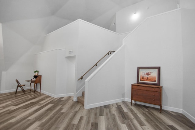 stairs with hardwood / wood-style floors and lofted ceiling