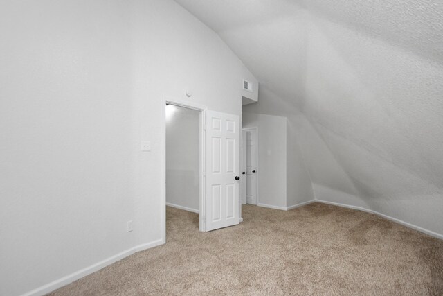 bonus room with light colored carpet and lofted ceiling