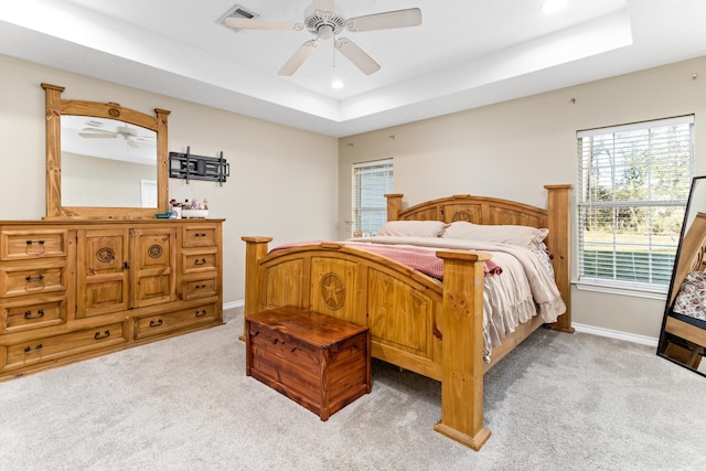 carpeted bedroom featuring ceiling fan and a raised ceiling