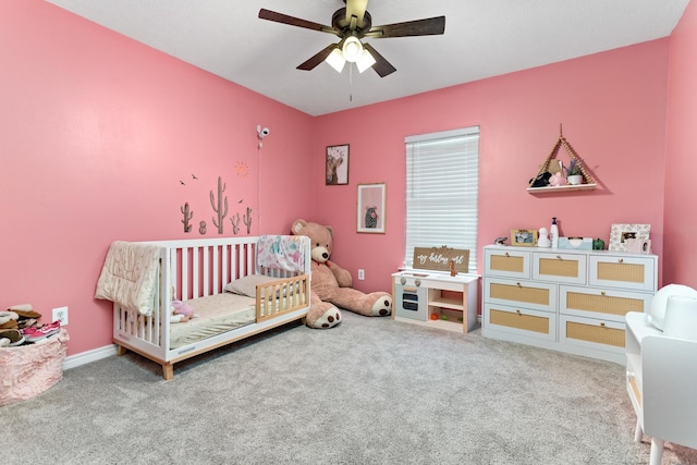 carpeted bedroom featuring ceiling fan and a nursery area