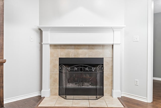 room details with hardwood / wood-style floors and a tiled fireplace