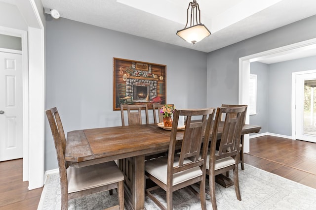 dining space featuring hardwood / wood-style floors and a stone fireplace