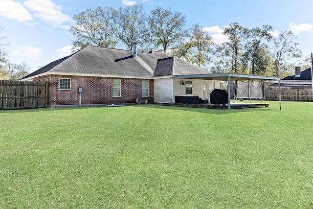 back of property featuring a trampoline and a yard