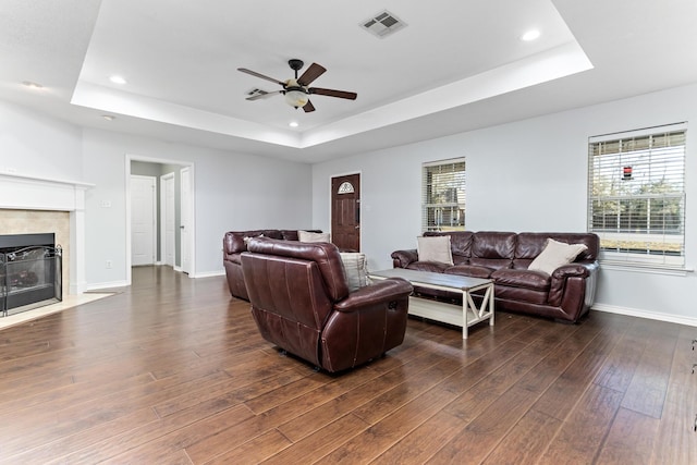 living room with ceiling fan, dark hardwood / wood-style floors, and a raised ceiling