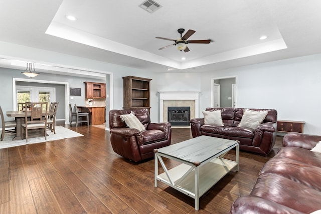 living room with ceiling fan, dark hardwood / wood-style floors, and a tray ceiling