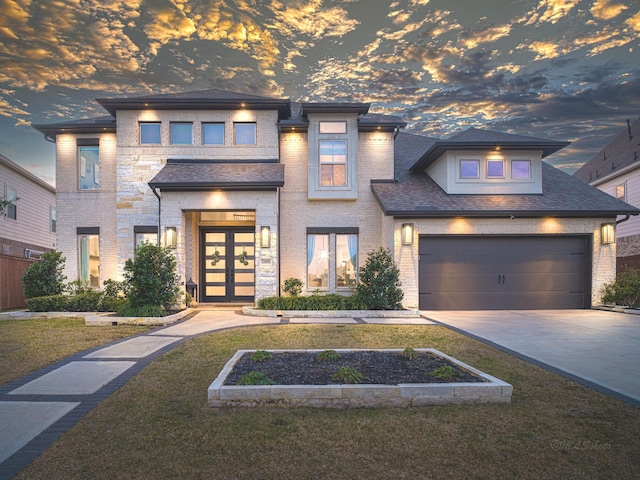 prairie-style house featuring a garage, a lawn, and french doors