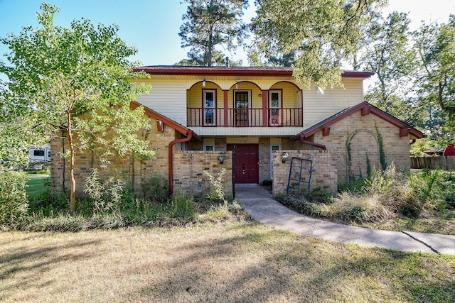 view of front facade with a balcony and a front yard