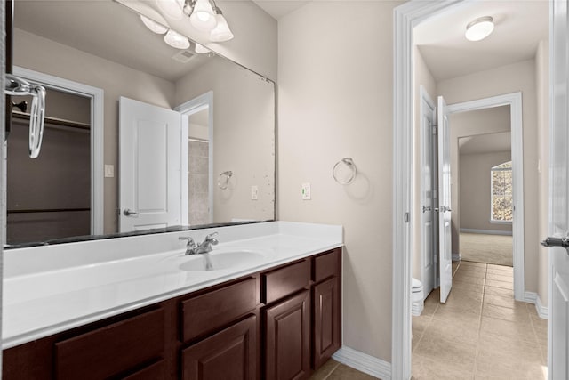 bathroom with toilet, vanity, and tile patterned flooring