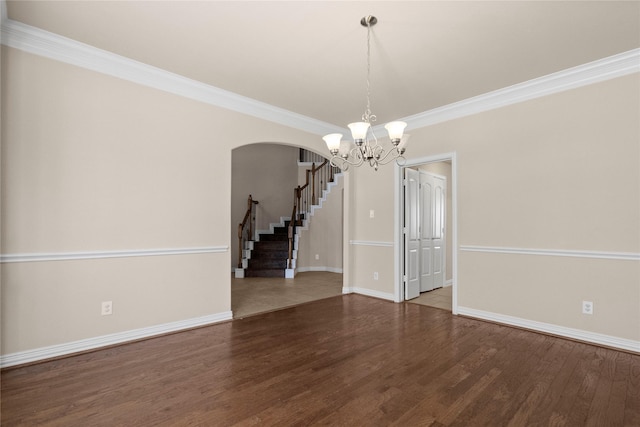 empty room featuring hardwood / wood-style flooring, a chandelier, and crown molding