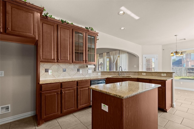 kitchen featuring pendant lighting, sink, dishwashing machine, a kitchen island, and decorative backsplash