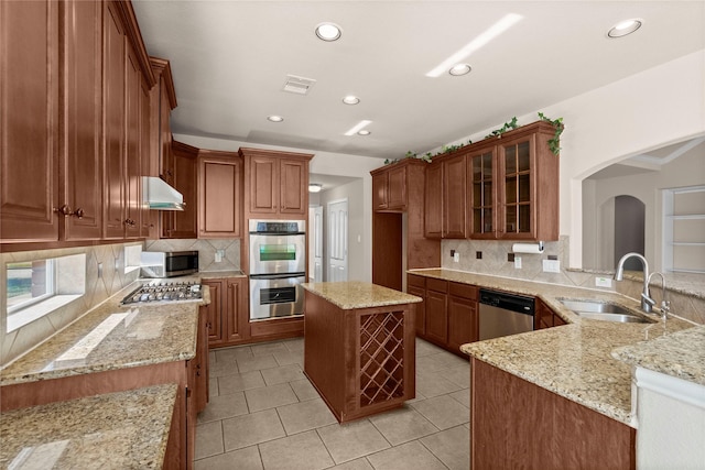 kitchen with light stone countertops, stainless steel appliances, sink, backsplash, and kitchen peninsula