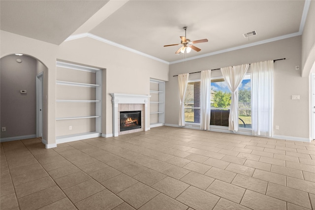 unfurnished living room featuring built in shelves, ceiling fan, a fireplace, and tile patterned flooring