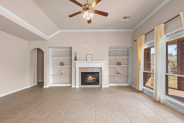 2511 Orchid Creek Dr, Pearland, TX 77584 - unfurnished living room featuring built in shelves, a tiled fireplace, light tile patterned flooring, crown molding, and ceiling fan