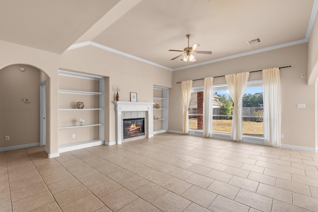 2511 Orchid Creek Dr, Pearland, TX 77584 - unfurnished living room featuring built in shelves, a ceiling fan, a tiled fireplace, tile patterned flooring, and crown molding