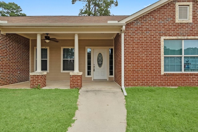 view of exterior entry with a lawn, ceiling fan, and covered porch