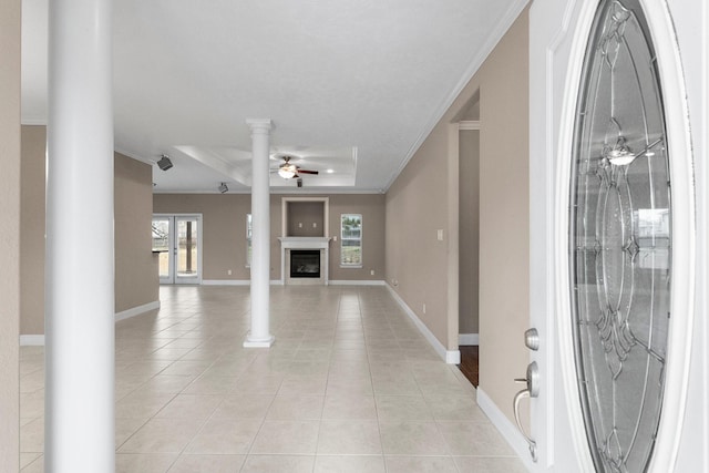 foyer entrance featuring light tile patterned floors, ornamental molding, a tray ceiling, ceiling fan, and decorative columns