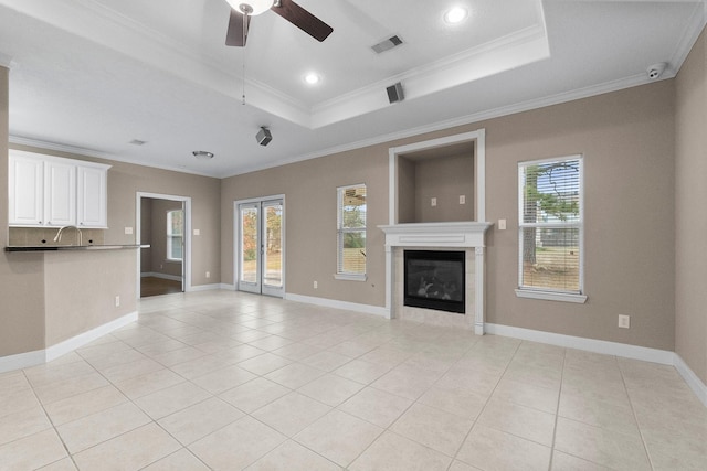 unfurnished living room with a tray ceiling, ornamental molding, and light tile patterned flooring