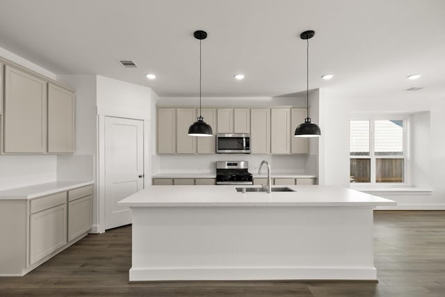 kitchen with pendant lighting, dark hardwood / wood-style flooring, sink, an island with sink, and stainless steel appliances