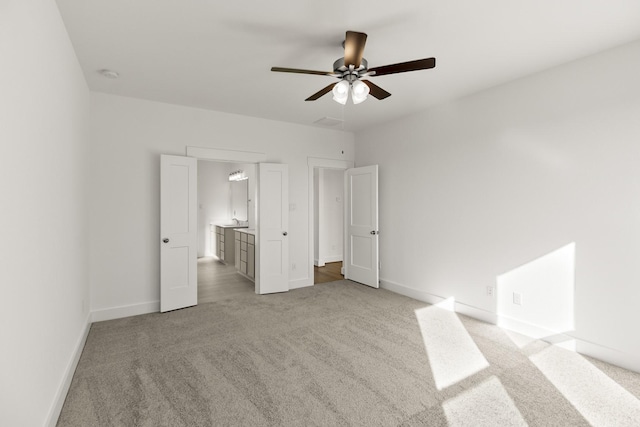 unfurnished bedroom featuring ceiling fan, ensuite bath, and light carpet