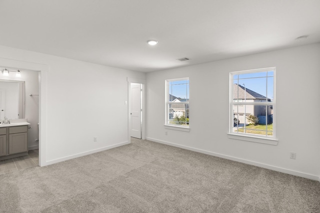 unfurnished bedroom featuring light colored carpet and ensuite bath