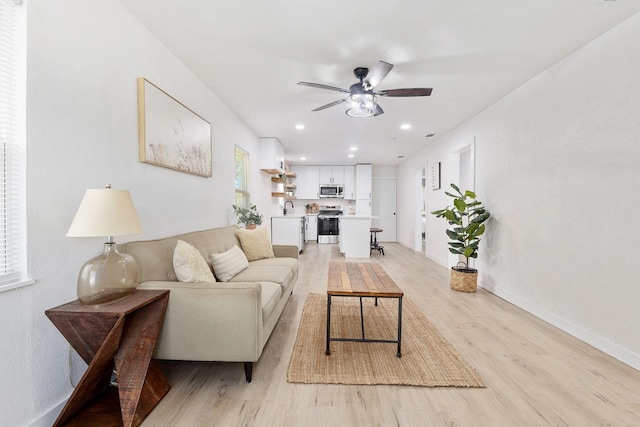 living room with sink, light hardwood / wood-style floors, and ceiling fan