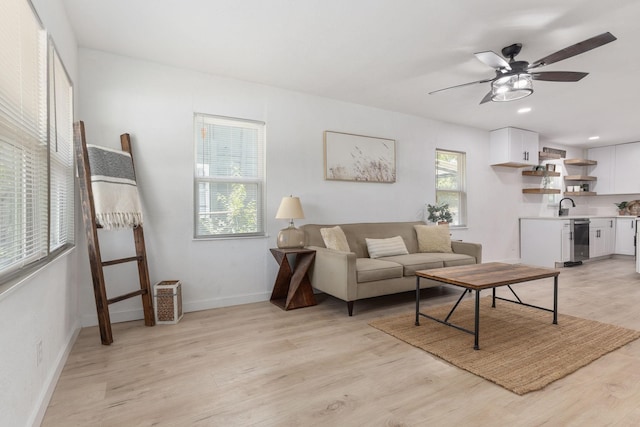 living room featuring sink, ceiling fan, and light hardwood / wood-style flooring