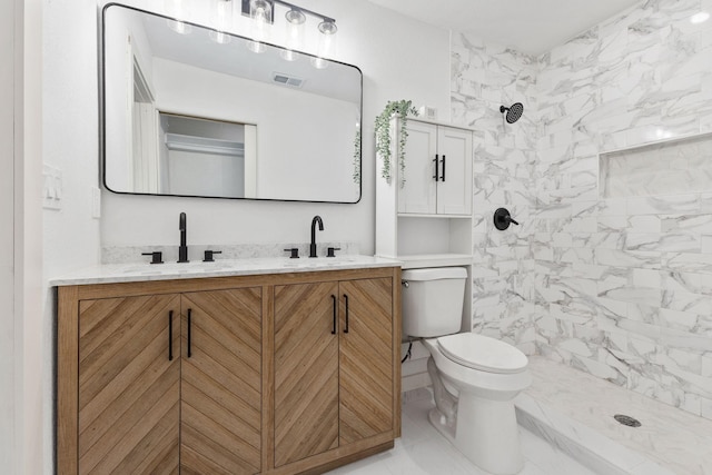 bathroom featuring vanity, toilet, and a tile shower