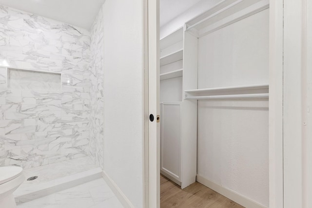 bathroom with hardwood / wood-style floors, tiled shower, and toilet