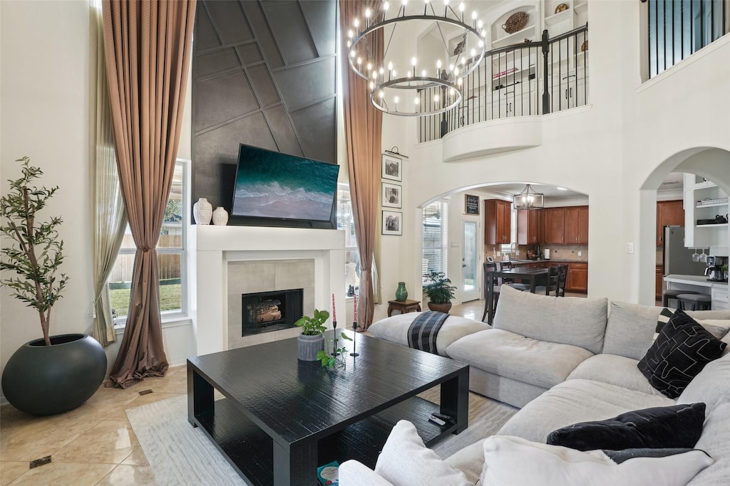 living room with light tile patterned floors, a towering ceiling, a fireplace, and a chandelier