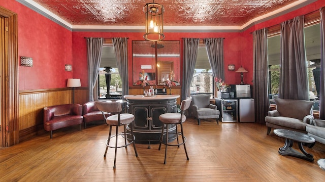 bar with parquet floors, ornamental molding, and pendant lighting