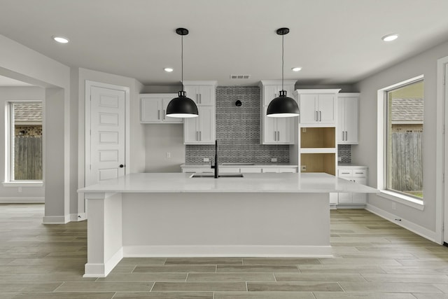 10807 Lighthouse Peak Trce, Richmond, TX 77406 - kitchen featuring white cabinets, a sink, baseboards, a large island, and light wood finished floors