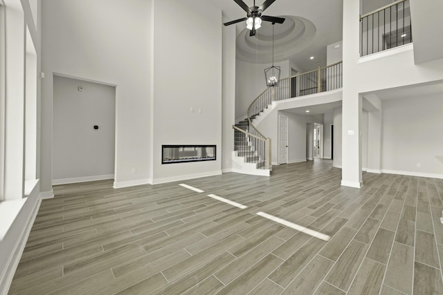 10807 Lighthouse Peak Trce, Richmond, TX 77406 - unfurnished living room featuring a high ceiling, stairs, baseboards, wood finished floors, and a chandelier
