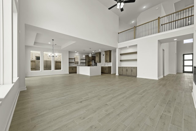 26515 Castra Crescent Trl, Richmond, TX 77406 - unfurnished living room with a chandelier, ceiling fan, recessed lighting, light wood-style flooring, and a high ceiling