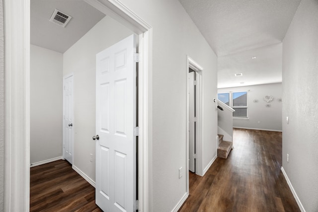 hallway with a textured ceiling and dark hardwood / wood-style flooring