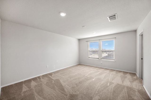 empty room featuring a textured ceiling and light carpet